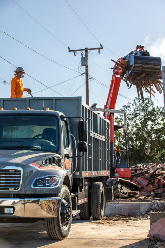 FMG hauling truck with crew loading demolition material