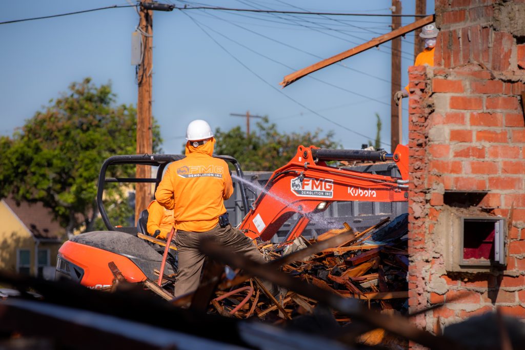 FMG crew member working beside a branded orange excavator